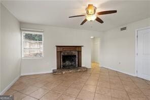 unfurnished living room featuring visible vents, baseboards, a fireplace with raised hearth, ceiling fan, and light tile patterned flooring
