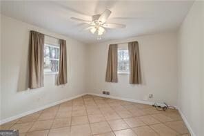 spare room featuring a wealth of natural light, baseboards, and a ceiling fan