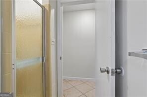full bathroom featuring baseboards, tile patterned flooring, and a shower with shower door