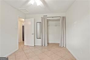 unfurnished bedroom featuring ceiling fan, a closet, and light tile patterned flooring