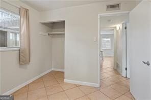 unfurnished bedroom featuring visible vents, a closet, baseboards, and light tile patterned flooring