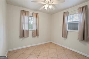 unfurnished room with baseboards, a ceiling fan, and tile patterned flooring