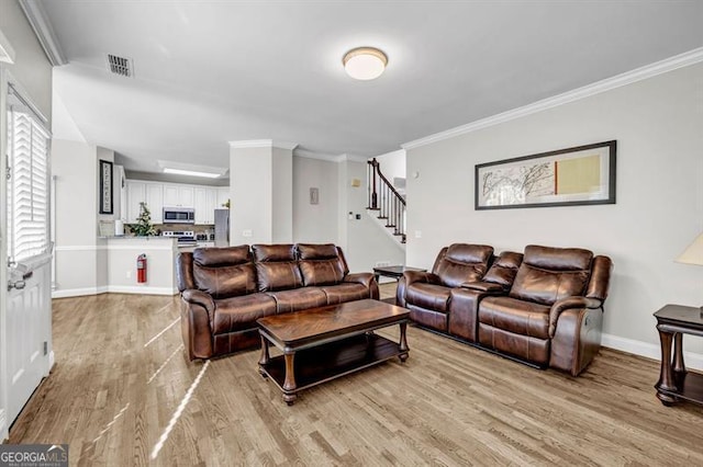 3139 Players Dr, Jonesboro, GA 30236 - living room featuring light wood-style floors, crown molding, baseboards, and stairs