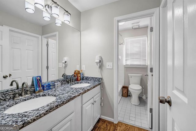 3139 Players Dr, Jonesboro, GA 30236 - bathroom featuring double vanity, toilet, bathing tub / shower combination, baseboards, and wood finished floors