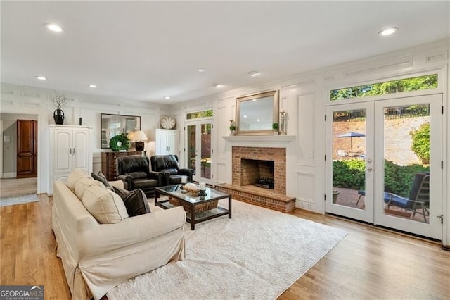 5520 Glen Errol Rd, Atlanta, GA 30327 - living room featuring french doors, light wood-type flooring, recessed lighting, a brick fireplace, and a decorative wall