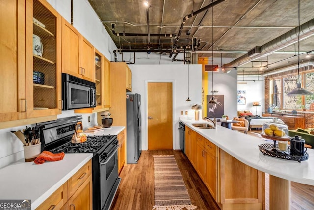 kitchen with glass insert cabinets, light countertops, dark wood finished floors, and black appliances