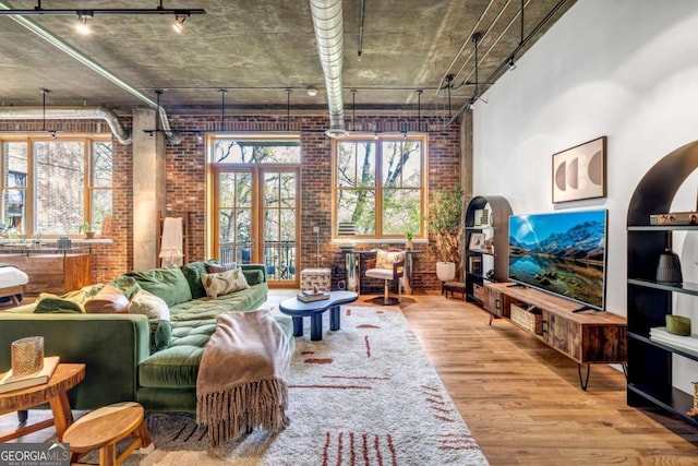 living area with wood finished floors, rail lighting, and brick wall