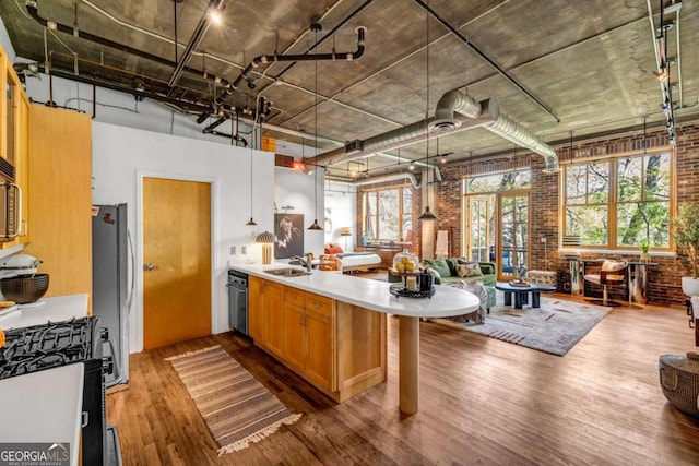 kitchen with range with gas cooktop, brick wall, a sink, open floor plan, and a peninsula