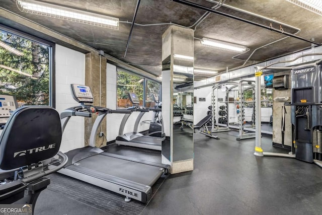 workout area featuring concrete block wall and a wealth of natural light
