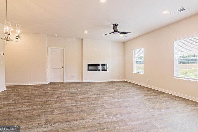 308 Brooks Dr Unit 80, Fairburn, GA 30213 - unfurnished living room with a chandelier, a ceiling fan, wood finished floors, recessed lighting, and a glass covered fireplace