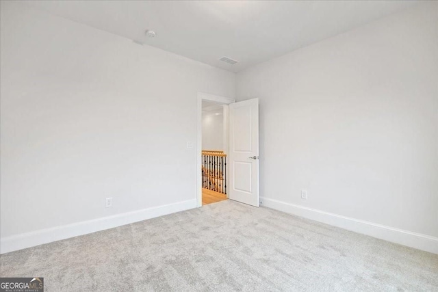 carpeted spare room featuring visible vents and baseboards