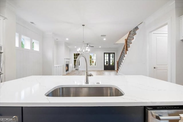 kitchen with a sink, open floor plan, recessed lighting, light stone countertops, and a lit fireplace