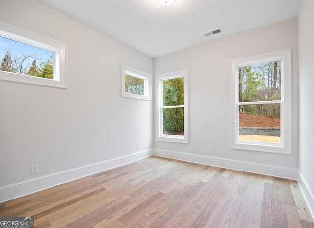 unfurnished room with light wood-type flooring, baseboards, and visible vents