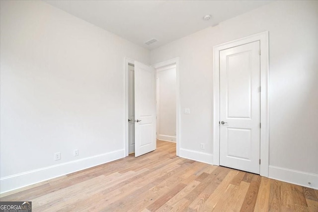 unfurnished bedroom with light wood finished floors, baseboards, and visible vents