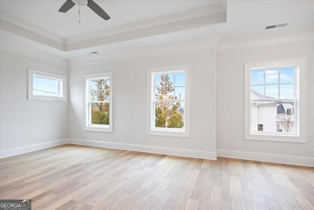 unfurnished room with visible vents, baseboards, a raised ceiling, ceiling fan, and light wood-style floors