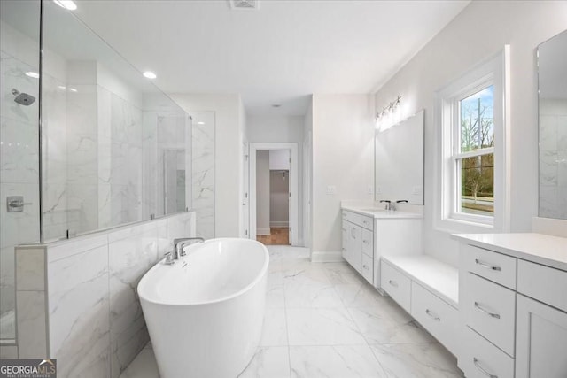 bathroom featuring a soaking tub, vanity, marble finish floor, a marble finish shower, and baseboards