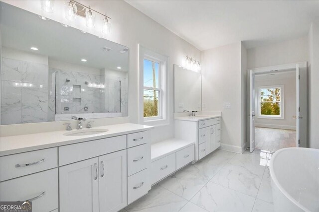 full bath featuring a sink, a tile shower, marble finish floor, and a freestanding tub