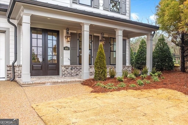 property entrance featuring brick siding, french doors, and covered porch