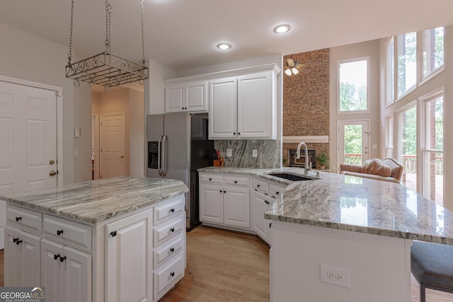 516 Turner Rd, Concord, GA 30206 - kitchen with a sink, stainless steel refrigerator with ice dispenser, a peninsula, white cabinets, and light stone counters