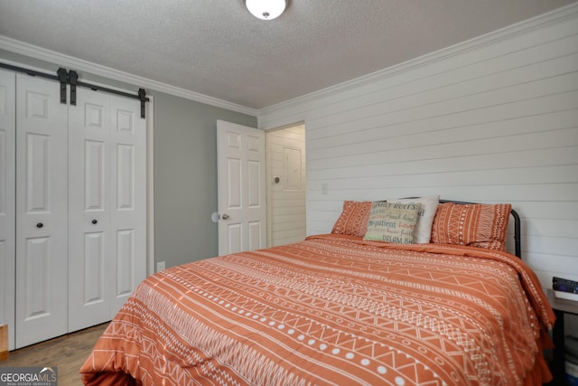 480 Friar Tuck Cir, Covington, GA 30014 - bedroom featuring a closet, a barn door, a textured ceiling, crown molding, and wood finished floors