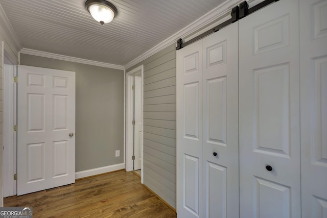 480 Friar Tuck Cir, Covington, GA 30014 - unfurnished bedroom featuring a closet, baseboards, a barn door, dark wood-style flooring, and crown molding