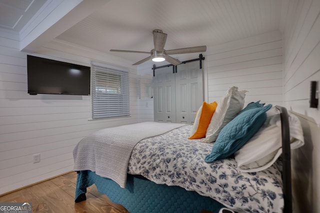 480 Friar Tuck Cir, Covington, GA 30014 - bedroom with wood walls, ceiling fan, a barn door, and wood finished floors