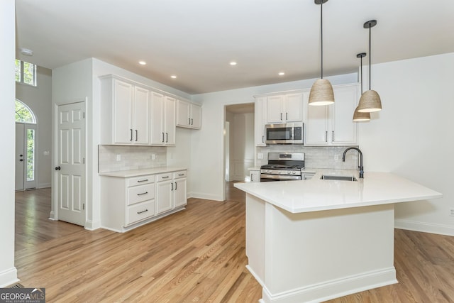 8660 Anchor On Lanier Ct, Gainesville, GA 30506 - kitchen with appliances with stainless steel finishes, a sink, light wood finished floors, decorative backsplash, and a peninsula