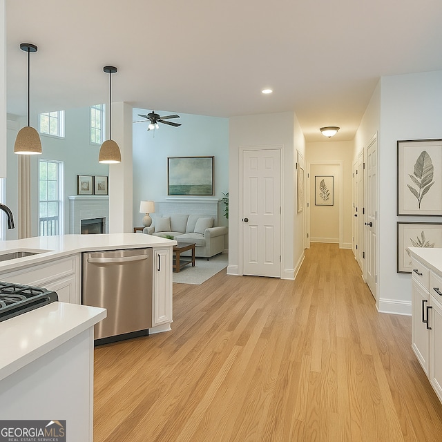 8660 Anchor On Lanier Ct, Gainesville, GA 30506 - kitchen with stainless steel dishwasher, a sink, a ceiling fan, white cabinetry, and a fireplace
