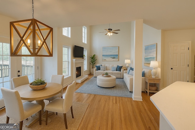 8660 Anchor On Lanier Ct, Gainesville, GA 30506 - dining space with light wood-style flooring, a lit fireplace, a ceiling fan, a chandelier, and baseboards