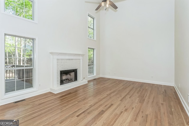 8660 Anchor On Lanier Ct, Gainesville, GA 30506 - unfurnished living room with a towering ceiling, light wood-style floors, baseboards, a brick fireplace, and a ceiling fan