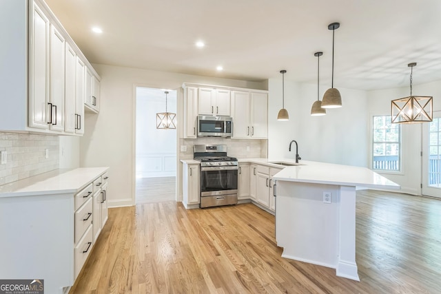 8660 Anchor On Lanier Ct, Gainesville, GA 30506 - kitchen featuring appliances with stainless steel finishes, a peninsula, a sink, tasteful backsplash, and light wood-style flooring