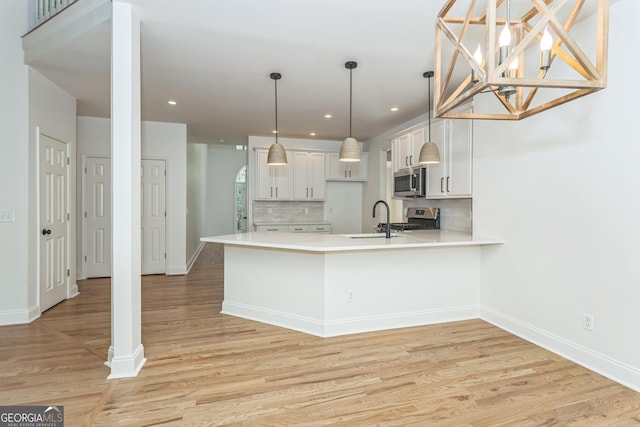 8660 Anchor On Lanier Ct, Gainesville, GA 30506 - kitchen featuring stainless steel appliances, a sink, light countertops, a peninsula, and tasteful backsplash