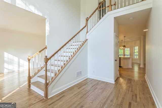 8660 Anchor On Lanier Ct, Gainesville, GA 30506 - stairway featuring wood finished floors, baseboards, a high ceiling, and a chandelier