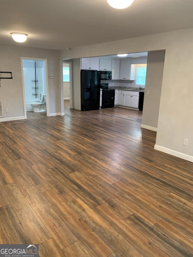 2467 Shady Grove Rd, Carrollton, GA 30116 - unfurnished living room featuring dark wood-style flooring, baseboards, and a sink