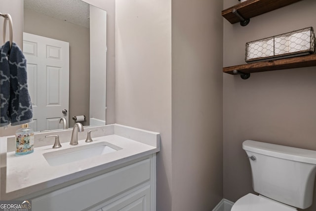 bathroom with toilet, vanity, and a textured ceiling