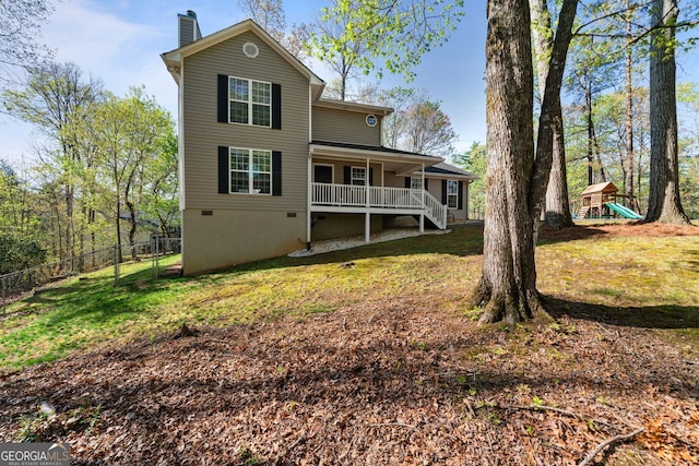 rear view of house with a chimney, a lawn, crawl space, fence, and a playground