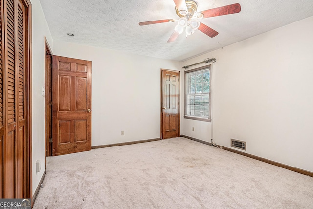unfurnished bedroom with carpet flooring, a textured ceiling, and visible vents