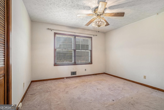 spare room with baseboards, carpet flooring, a textured ceiling, and visible vents