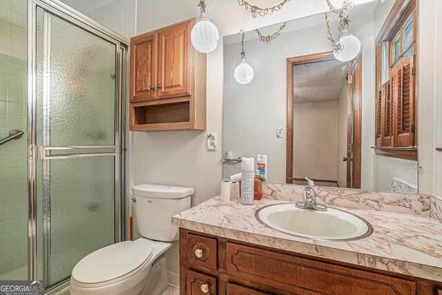 full bathroom featuring vanity, a shower stall, and toilet