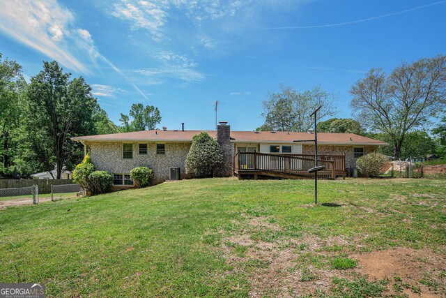 back of house featuring a lawn, a wooden deck, brick siding, and fence