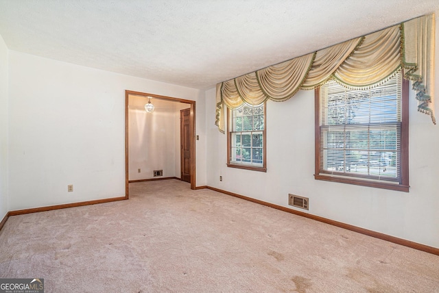 spare room featuring carpet floors, visible vents, and baseboards