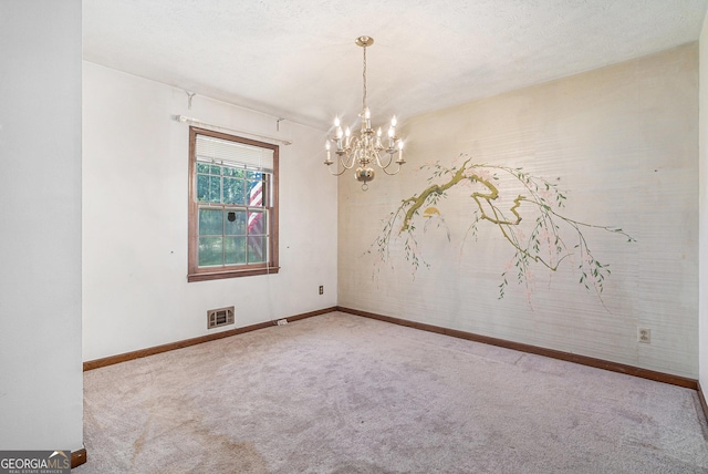 carpeted spare room with visible vents, baseboards, and a notable chandelier