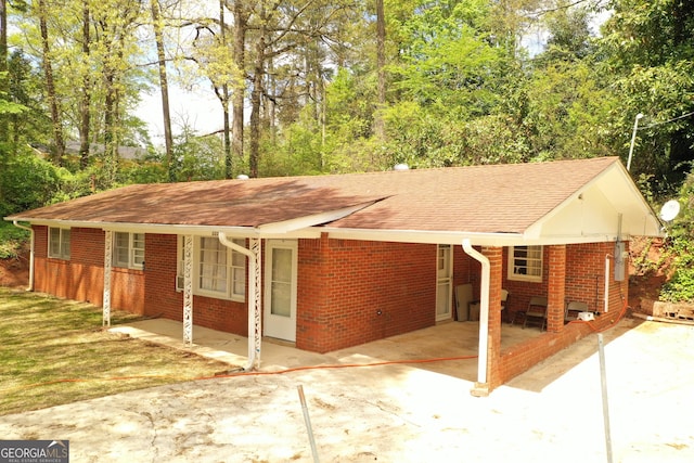 exterior space featuring an attached carport, brick siding, driveway, and a shingled roof