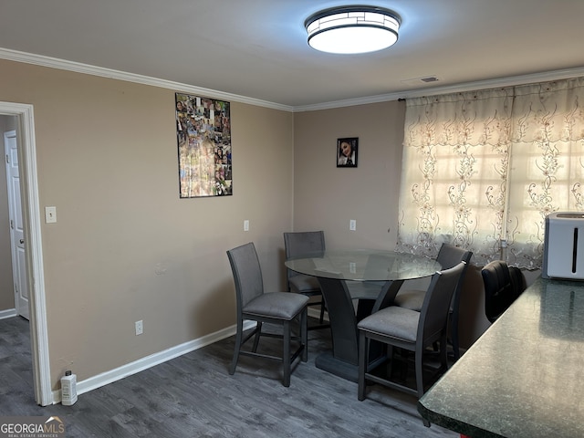 dining space with crown molding, baseboards, and wood finished floors