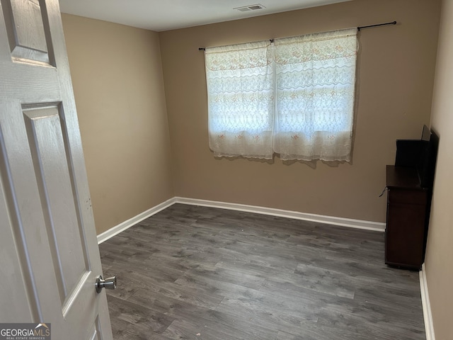 spare room with baseboards, dark wood finished floors, and visible vents