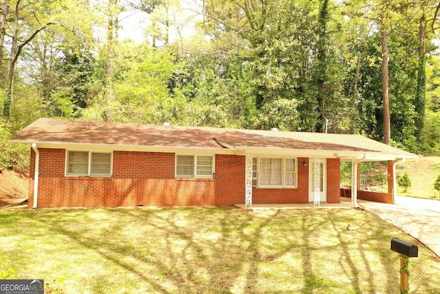 ranch-style house featuring a carport, concrete driveway, a front yard, and brick siding
