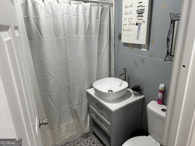 full bath featuring tile walls, toilet, curtained shower, and vanity