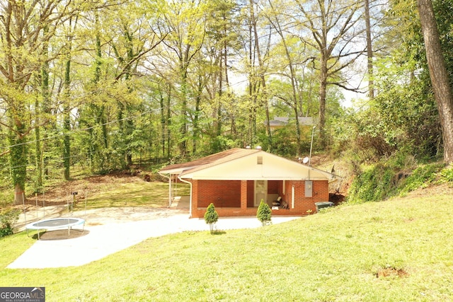 view of outbuilding featuring a view of trees, a trampoline, and a porch