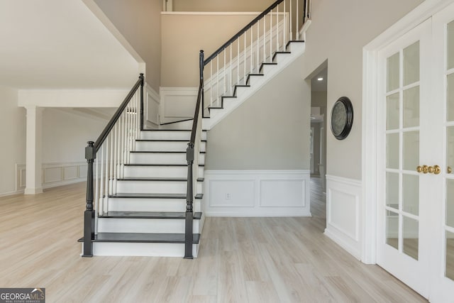2635 Stonehill Dr, Cumming, GA 30041 - stairs with a decorative wall, wood finished floors, a towering ceiling, and a wainscoted wall
