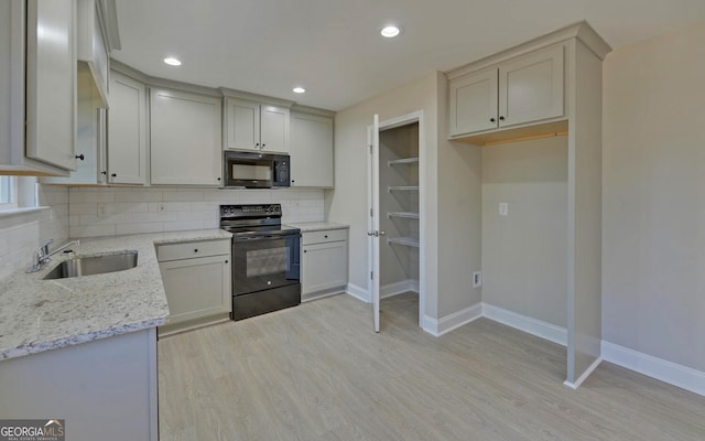 kitchen with baseboards, a sink, decorative backsplash, and black appliances